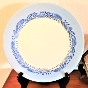 May include: A light blue ceramic plate with a white center and a blue floral design around the rim.