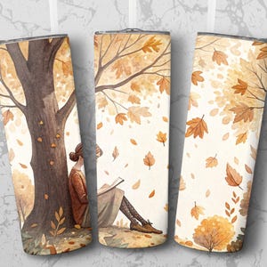 Peut inclure: Ensemble de trois gobelets en acier inoxydable avec une illustration à l'aquarelle d'une personne lisant sous un arbre en automne. Le design présente un arbre brun, des feuilles qui tombent et une personne en manteau et jupe bruns.