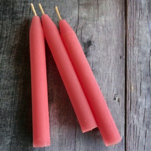 May include: Three pink  candles with natural wicks.