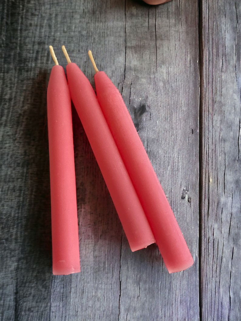 May include: Three pink  candles with natural wicks.