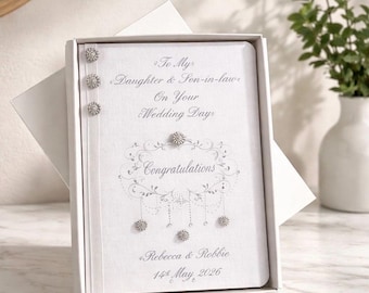 May include: A white wedding card in a white box. The card reads "To My Daughter & Son-in-law On Your Wedding Day Congratulations Rebecca & Robbie 14th May 2026". The card is decorated with silver embellishments.