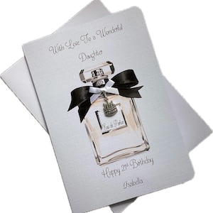 May include: A light gray birthday card with a perfume bottle illustration. The bottle has a black bow and a silver charm. Text reads "With Love To a Wonderful Daughter", "Happy 21st Birthday", and "Isabella".