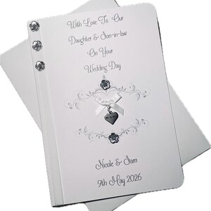 May include: A white wedding card with the text "With Love To Our Daughter & Son-in-law On Your Wedding Day". The card features decorative embellishments, a ribbon, and the names "Nicole & Sam" with the date "9th May 2026".