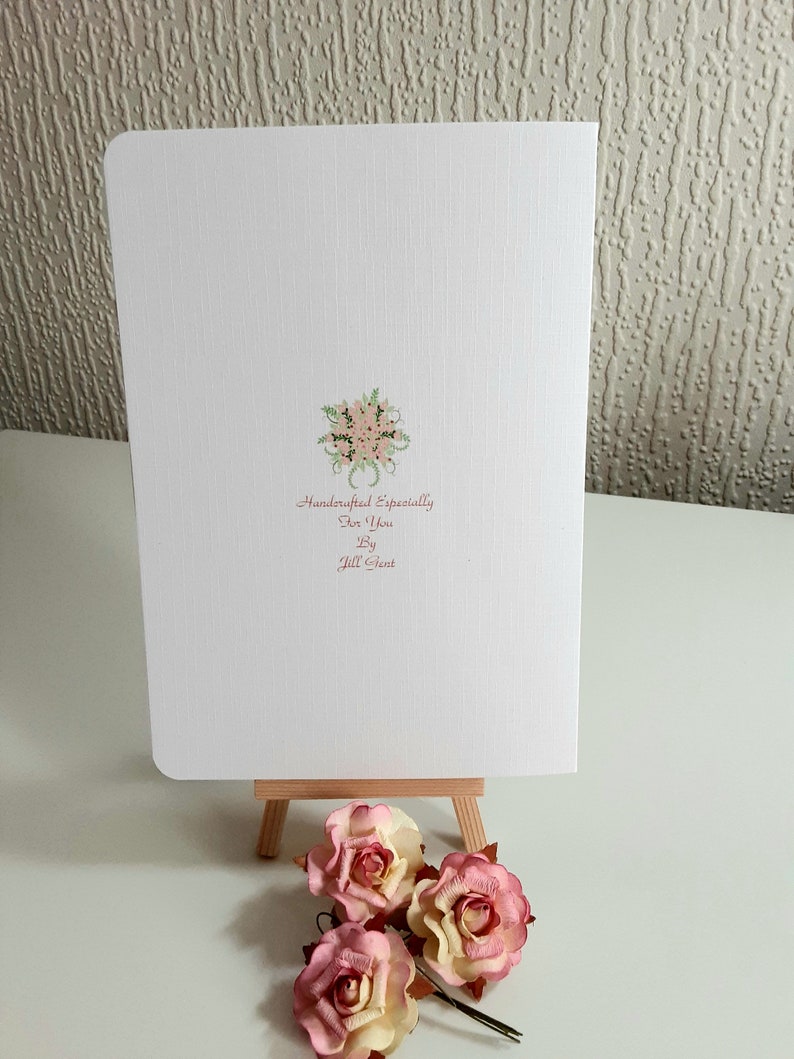 May include: A white card with a pink floral design and the text "Handcrafted Especially for You by Jill Grant".