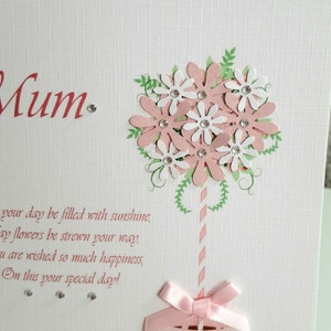 May include: A pink and white card with a flower bouquet design and the text "With Love To A Wonderful Mum. Your day be filled with sunshine, May flowers be strewn your way, You are wished so much happiness, On this your special day!"