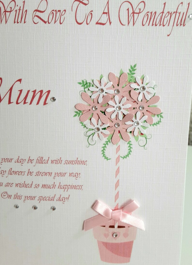 May include: A pink and white card with a flower bouquet design and the text "With Love To A Wonderful Mum. Your day be filled with sunshine, May flowers be strewn your way, You are wished so much happiness, On this your special day!"