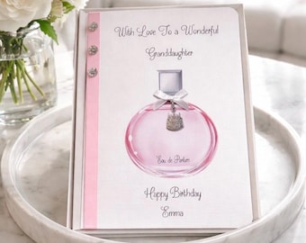 Może przedstawiać: Kartka urodzinowa dla wnuczki, z ilustracją różowego flakonu perfum. Na kartce napisano "With Love To a Wonderful Granddaughter" i "Happy Birthday Emma". Ozdobiona różową wstążką i błyszczącymi kamieniami.