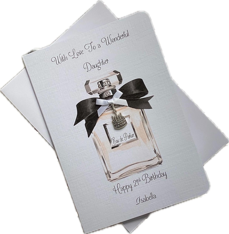 May include: A birthday card for a daughter, featuring a perfume bottle illustration with a black bow and a charm. The card reads "With Love To a Wonderful Daughter" and "Happy 21st Birthday, Isabella."