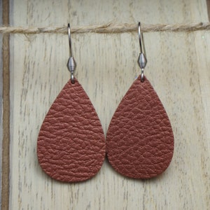 May include: A pair of brown leather teardrop earrings with silver hooks.