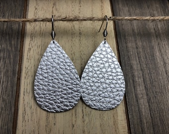May include: A pair of silver teardrop-shaped earrings with a textured leather finish.
