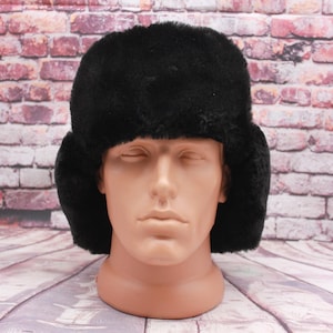 May include: A black faux fur ushanka hat with ear flaps. The hat is on a mannequin head.