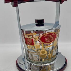 May include: Vintage cocktail ice bucket with a chrome and red handle and base. The clear glass bucket has gold lettering and illustrations for cocktail recipes, including "Whiskey Sour" and "Martini".