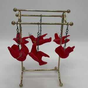 May include: A gold metal stand with six red velvet birds hanging from it. The birds are attached to the stand with chains.