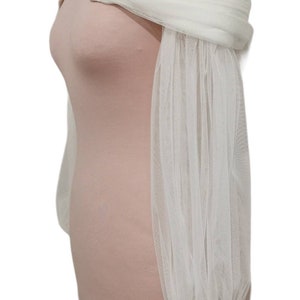 Puede incluir: Top blanco de tul con hombros descubiertos y mangas largas abullonadas. Las mangas son transparentes y tienen un pu&ntilde;o fruncido en la mu&ntilde;eca.