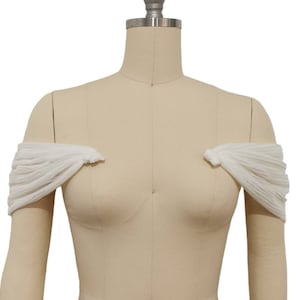 May include: White off-the-shoulder fabric sleeves for a wedding dress or other formal attire.