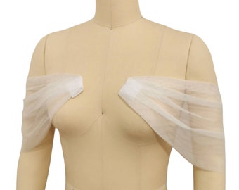 May include: White tulle off-the-shoulder bridal bolero. The bolero is made of soft, sheer tulle and has a delicate, flowing design.