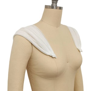May include: White tulle shoulder straps for a wedding dress or other formal attire. The straps are gathered and tied at the shoulders.