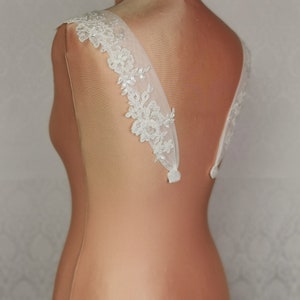 May include: White lace bridal straps with a sheer tulle backing. The straps are designed to be sewn onto a wedding dress.