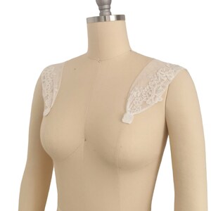 Puede incluir: Tirantes de hombro de encaje blanco con un delicado patr&oacute;n floral. Las tiras son de tela transparente y est&aacute;n dise&ntilde;adas para usarse sobre un vestido o una blusa.