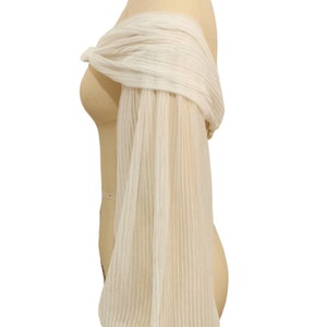 Puede incluir: Top blanco de hombros descubiertos con mangas largas, transparentes y a rayas.