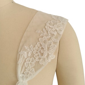 Puede incluir: Tela de tul blanco con un delicado ribete de encaje floral. El encaje presenta un dise&ntilde;o floral con peque&ntilde;as cuentas blancas.