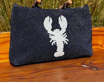 May include: A black beaded tote bag with a white lobster design and wooden handles.
