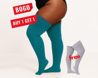 May include: A pair of teal ribbed over-the-knee socks worn on the legs and a pair of light gray ribbed over-the-knee socks displayed separately. The image includes red text labels that read BOGO, BUY 1 GET 1, and free.