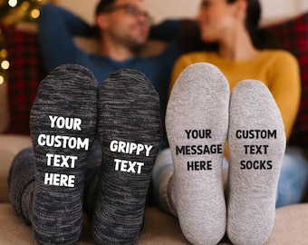 May include: A pair of gray socks and a pair of dark gray socks with custom text printed on the soles. The gray socks read "YOUR MESSAGE HERE" and "CUSTOM TEXT SOCKS". The dark gray socks read "YOUR CUSTOM TEXT HERE" and "GRIPPY TEXT".