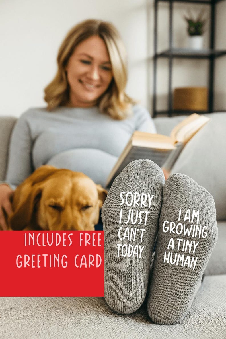 Puede incluir: Un par de calcetines de punto gris con texto blanco en las suelas. El calcet&iacute;n izquierdo dice SORRY I JUST CAN'T TODAY y el derecho dice I AM GROWING A TINY HUMAN. Los calcetines est&aacute;n confeccionados con un tejido suave y texturizado.