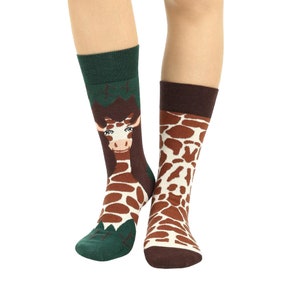 May include: A pair of colorful socks with a giraffe print. One sock has a green background with a giraffe's head peeking out, while the other sock has a brown background with a giraffe pattern.
