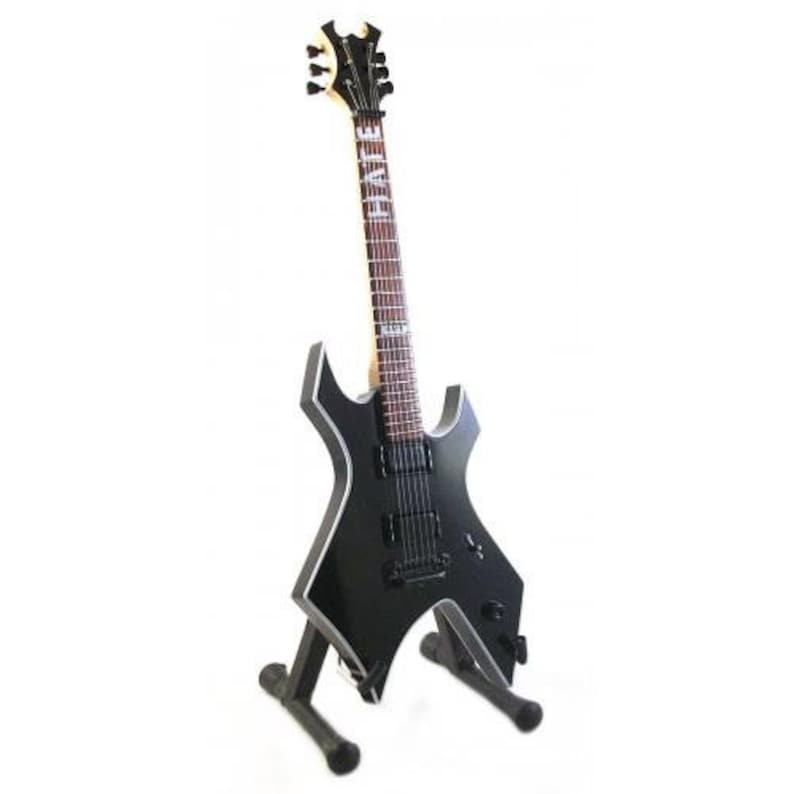 May include: Black electric guitar with a star-shaped body and a black and white finish. The guitar has a black headstock with a white "HATE" logo. The guitar is on a black stand.