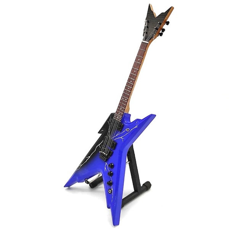 Puede incluir: Una guitarra el&eacute;ctrica azul y negra con un dise&ntilde;o de rayo en el cuerpo. La guitarra est&aacute; en un soporte negro.