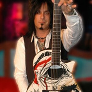 Puede incluir: Un hombre con el pelo largo y negro sostiene una guitarra el&eacute;ctrica blanca con detalles en negro y rojo. La guitarra tiene un dise&ntilde;o de calavera y huesos cruzados con las palabras "The Diaries" y "Rock" escritas en ella.