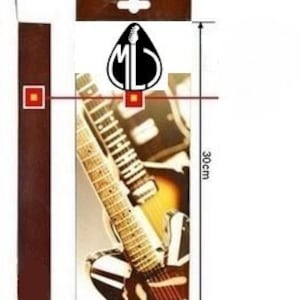 Puede incluir: Una correa de guitarra marr&oacute;n con un dise&ntilde;o de guitarra en blanco y negro. La correa mide 3 cm de ancho y 30 cm de largo. La correa tiene un logotipo que dice "ML".