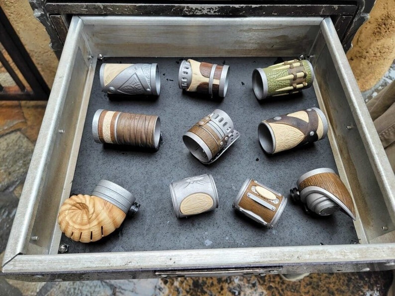 May include: A drawer filled with nine different leather and metal bracelets. The bracelets are all different colors and designs, and they are arranged in a neat row.