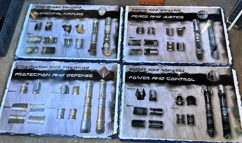 May include: Four slate tiles with different lightsaber parts and designs. Each tile has a title in a fictional language and an English translation. The titles are "Elemental Nature", "Peace and Justice", "Protection and Defense", and "Power and Control".