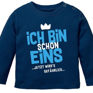 Könnte beinhalten: Ein dunkelblaues Langarmshirt mit einer weißen Krone und dem Text "Ich bin schon eins... jetzt wird's gefährlich..." in Blau.