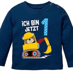 Könnte beinhalten: Ein marineblaues Langarmshirt mit einem gelben Baufahrzeug und einem Bären, der einen Helm trägt. Der Text "Ich bin jetzt 1" ist auf dem Shirt aufgedruckt.
