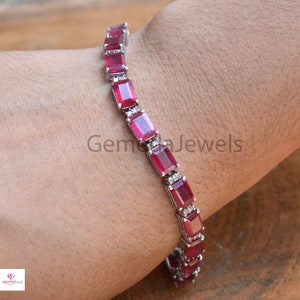 Peut inclure: Un bracelet de tennis en argent avec une rangée de pierres précieuses rectangulaires rouges et de petites pierres précieuses claires.