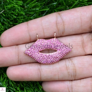 May include: A rose gold pendant charm in the shape of lips, encrusted with pink cubic zirconia stones.