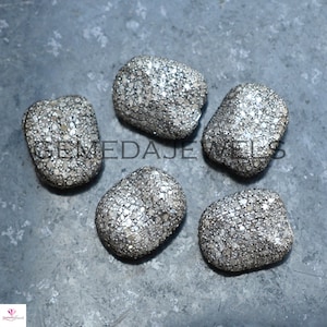 May include: Five silver oval-shaped beads with a textured surface covered in tiny silver dots.