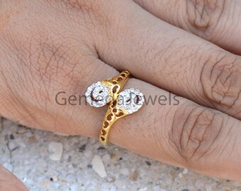 May include: A gold ring with two round, clear stones set in a delicate, openwork design.
