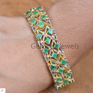 Peut inclure: Un bracelet jonc en or avec un motif géométrique orné de pierres précieuses émeraude verte et rose. Le bracelet est serti de petits diamants et présente un motif délicat et complexe.