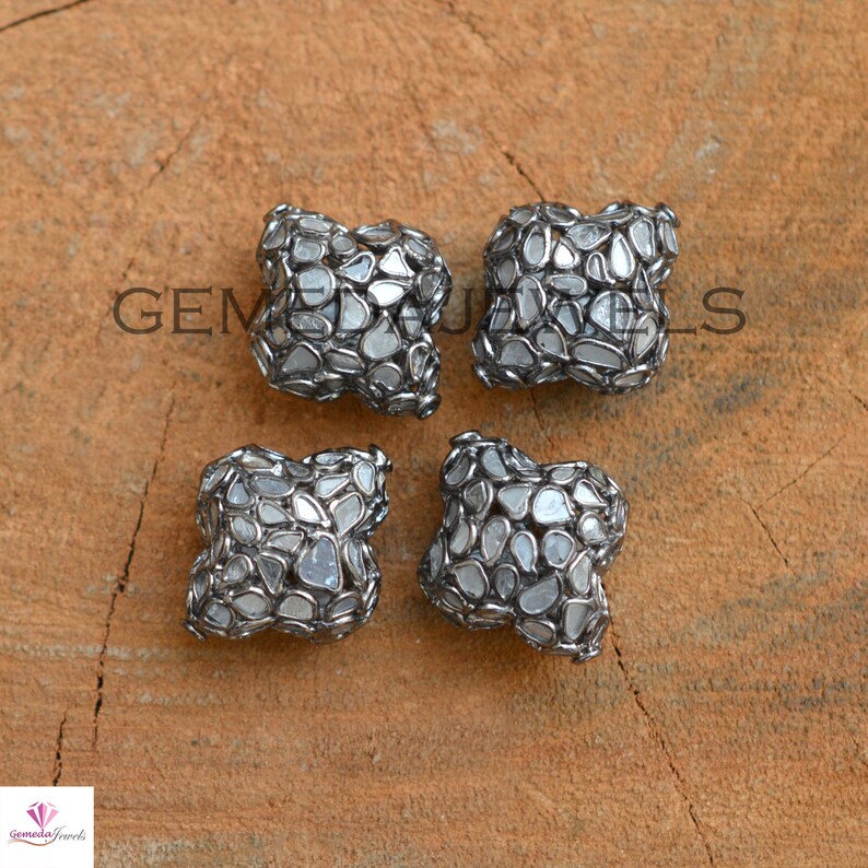 Puede incluir: Cuatro cuentas cuadradas plateadas y blancas con un dise&ntilde;o geom&eacute;trico. Cada cuenta est&aacute; hecha de muchos diamantes peque&ntilde;os de forma irregular engastados en plata.