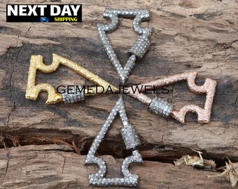May include: Four silver, gold, and rose gold arrow-shaped charms with pave diamond accents. The charms are arranged in a star shape on a wooden surface.