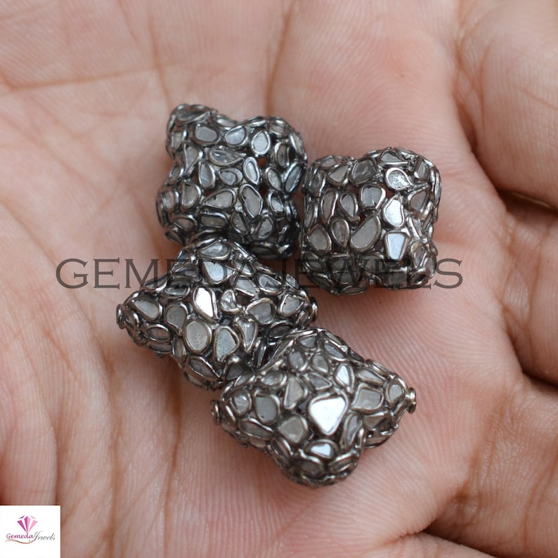 Puede incluir: Tres cuentas de plata y diamantes blancos. Las cuentas son de forma cuadrada y tienen un dise&ntilde;o geom&eacute;trico.