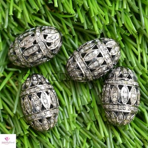 May include: Five oval-shaped silver beads with a delicate, intricate design. Each bead is covered in small, sparkling diamonds.