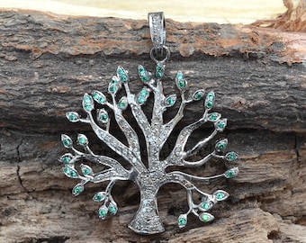 May include: A silver tree of life pendant with a black finish, adorned with small green and white gemstones. The pendant is designed in a circular shape and features intricate details.