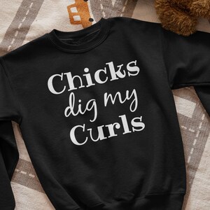 May include: Black sweatshirt with white text that reads "Chicks dig my curls".