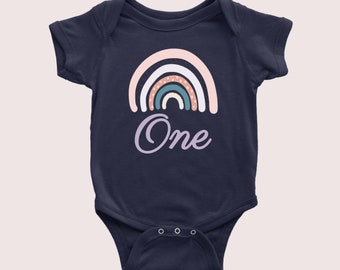 May include: A navy blue baby onesie with a rainbow design and the word "One" in purple script.